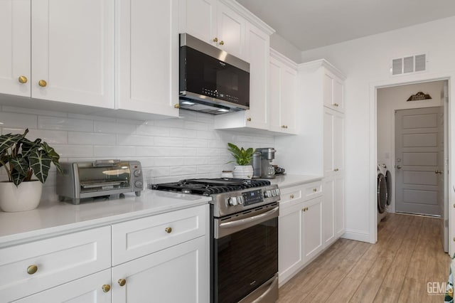 kitchen featuring appliances with stainless steel finishes, white cabinets, light countertops, and tasteful backsplash