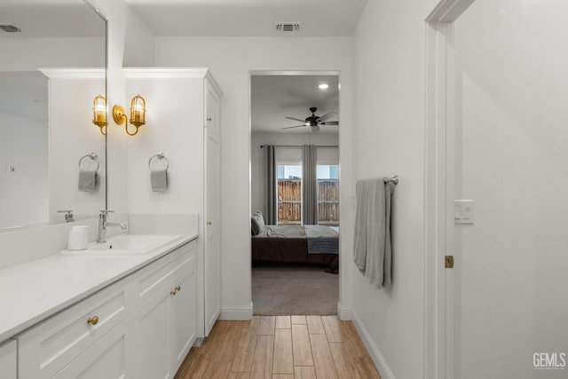 bathroom with a ceiling fan, wood finished floors, baseboards, vanity, and connected bathroom