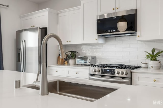 kitchen featuring appliances with stainless steel finishes, light countertops, white cabinets, and decorative backsplash