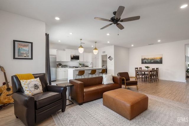 living area featuring light wood-style flooring, ceiling fan, recessed lighting, and baseboards
