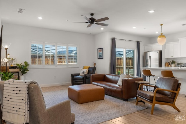living room featuring light wood-style floors, a ceiling fan, recessed lighting, and baseboards
