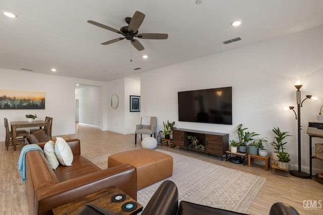 living room featuring light wood-style flooring, a ceiling fan, baseboards, and recessed lighting