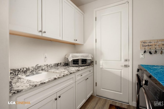 laundry area with cabinets, washing machine and dryer, sink, and dark wood-type flooring