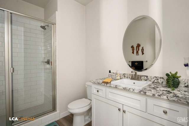 bathroom with hardwood / wood-style floors, vanity, a shower with shower door, and toilet