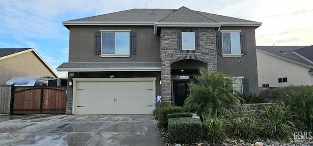 9211 Woodbrook Dr, Shafter, CA 93263 - view of front of home featuring an attached garage, stone siding, stucco siding, fence, and concrete driveway