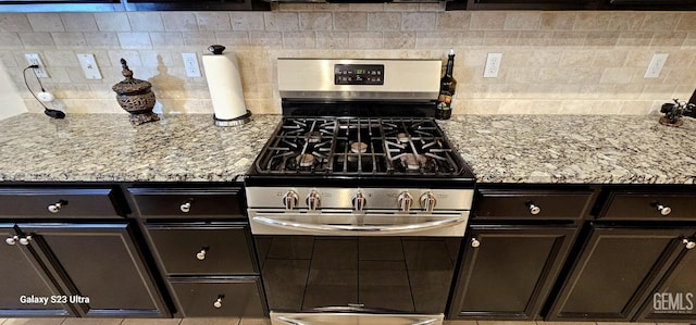 9211 Woodbrook Dr, Shafter, CA 93263 - kitchen with stainless steel range with gas stovetop, backsplash, light stone countertops, and dark brown cabinets