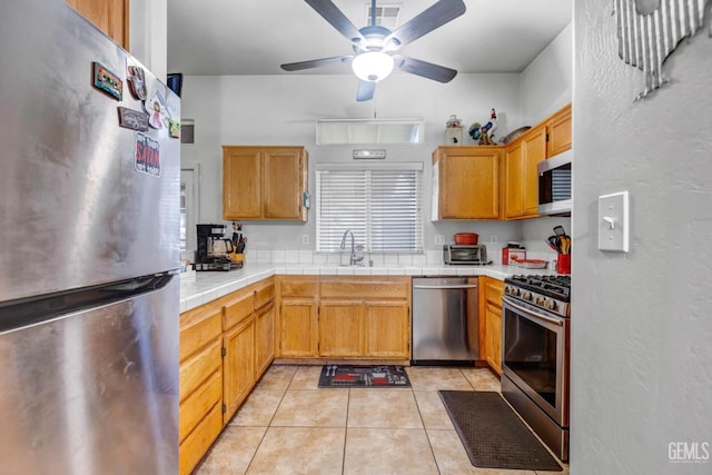 kitchen with visible vents, tile counters, appliances with stainless steel finishes, light tile patterned flooring, and a ceiling fan