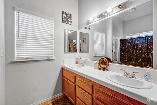 bathroom with double vanity, baseboards, and a sink