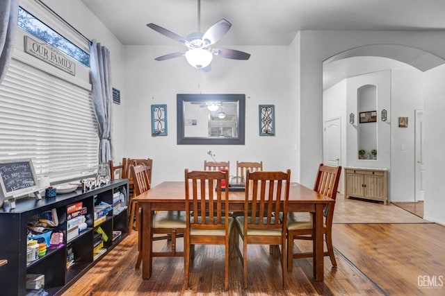 dining room featuring arched walkways, wood finished floors, and a ceiling fan