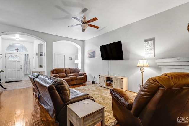 living room featuring ceiling fan, arched walkways, and hardwood / wood-style floors