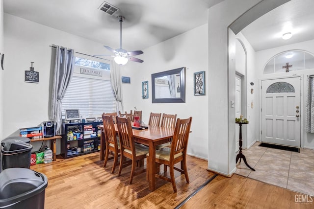 dining space with arched walkways, visible vents, a ceiling fan, and wood finished floors