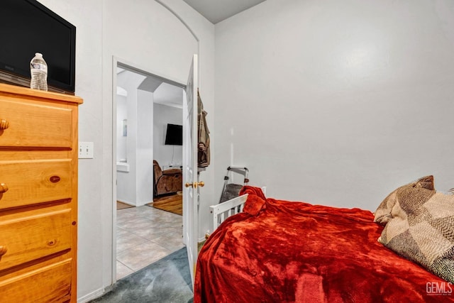 tiled bedroom featuring arched walkways and carpet floors