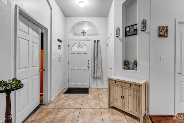 entrance foyer with light tile patterned floors and baseboards