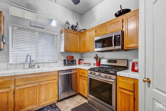 kitchen with a wealth of natural light, light tile patterned flooring, appliances with stainless steel finishes, and a sink