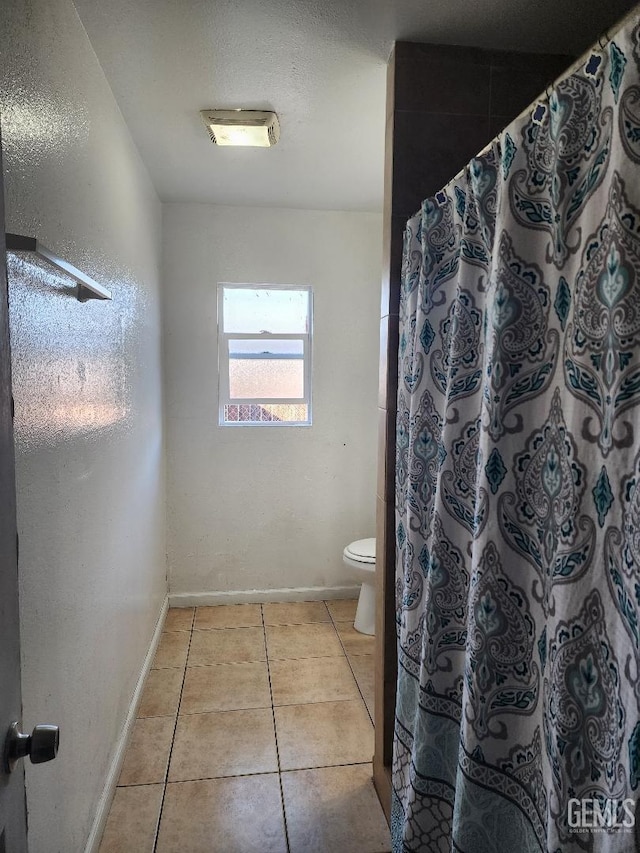 bathroom featuring toilet, tile patterned flooring, a shower with curtain, and a textured ceiling