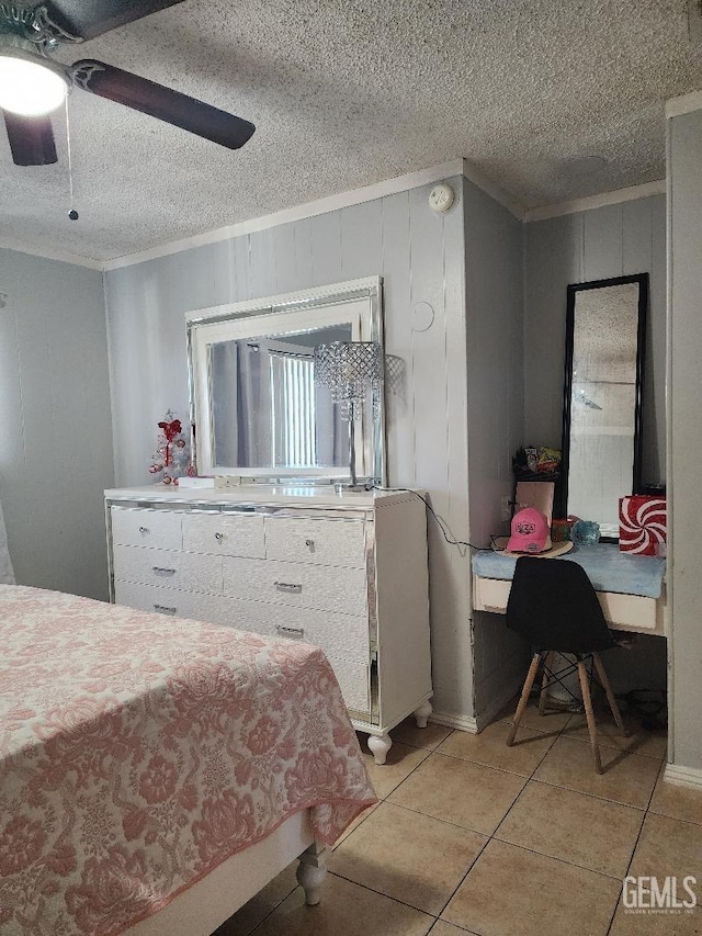 tiled bedroom with a textured ceiling, wood walls, ceiling fan, and crown molding