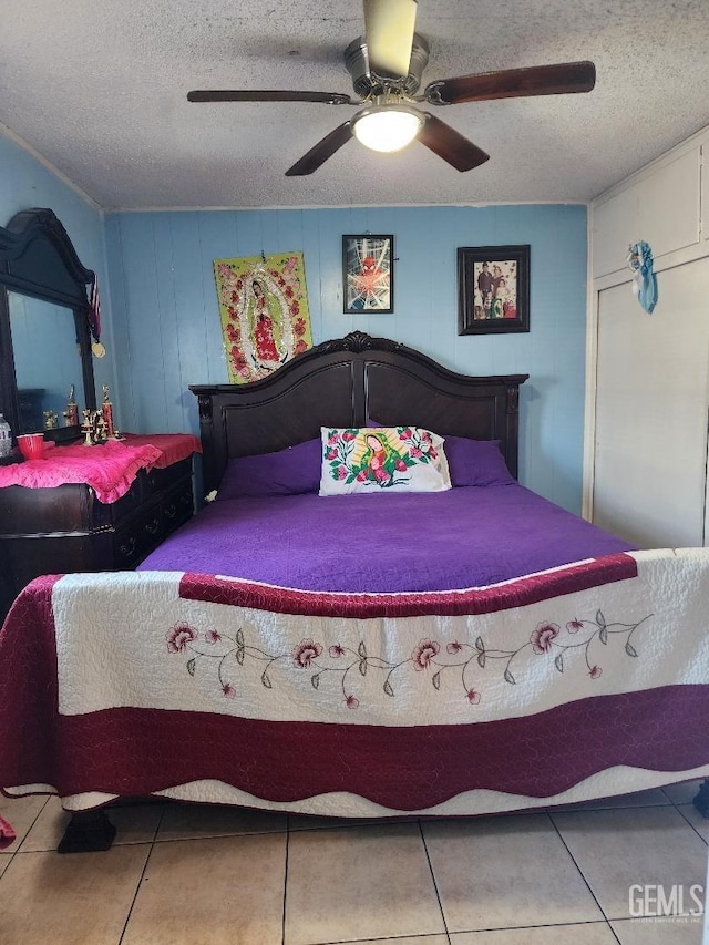 tiled bedroom with a textured ceiling, wood walls, and ceiling fan