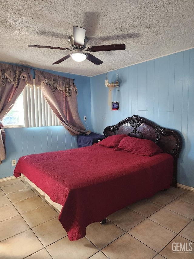 bedroom with tile patterned floors, a textured ceiling, ceiling fan, and wood walls