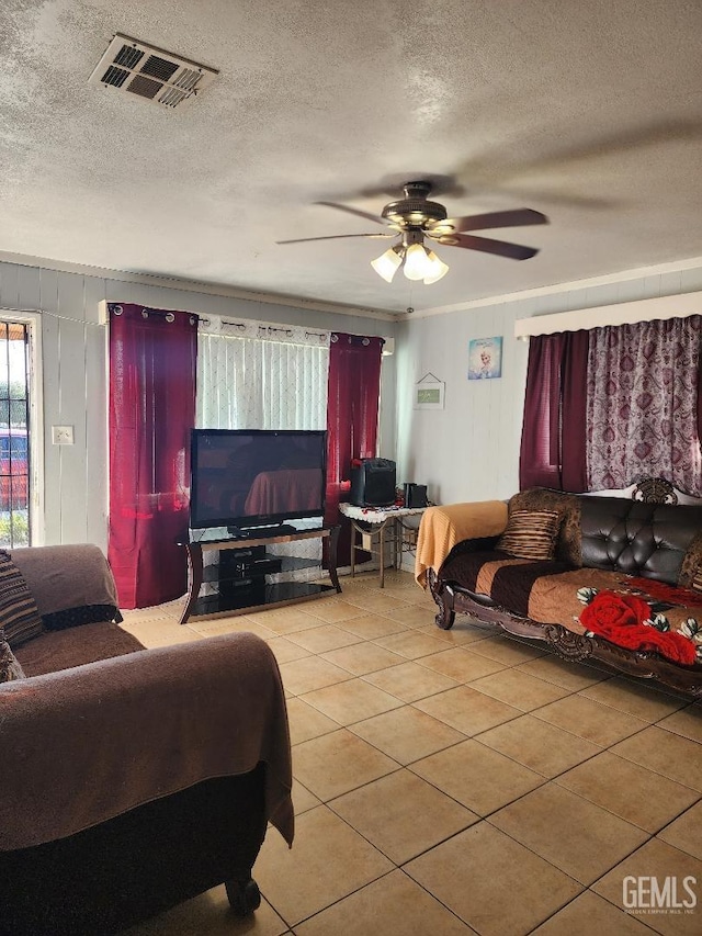 living room featuring a textured ceiling, ceiling fan, and light tile patterned floors