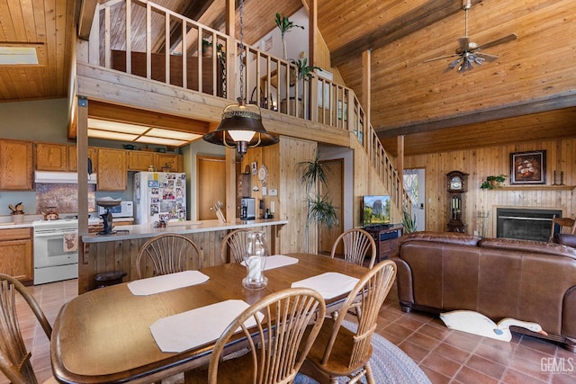 25001 Cannonero Ct, Tehachapi, CA 93561 - dining space with high vaulted ceiling, a wood ceiling with exposed beams, wood walls, light tile patterned flooring, and a glass covered fireplace