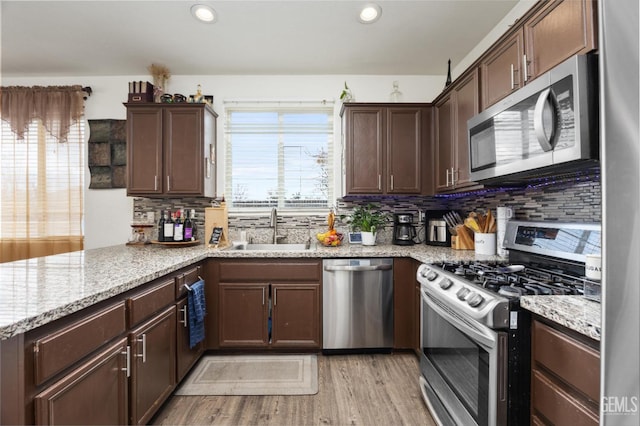 kitchen featuring light stone counters, appliances with stainless steel finishes, sink, and dark brown cabinets