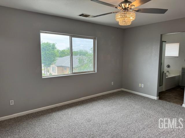 carpeted spare room with baseboards, visible vents, and ceiling fan