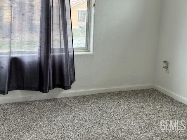 spare room featuring carpet floors and baseboards