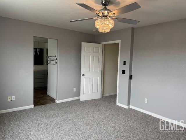 unfurnished bedroom featuring connected bathroom, baseboards, a ceiling fan, and carpet
