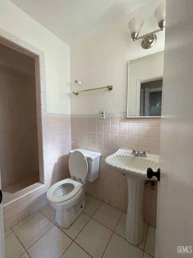 bathroom featuring tile patterned flooring, tiled shower, toilet, and tile walls