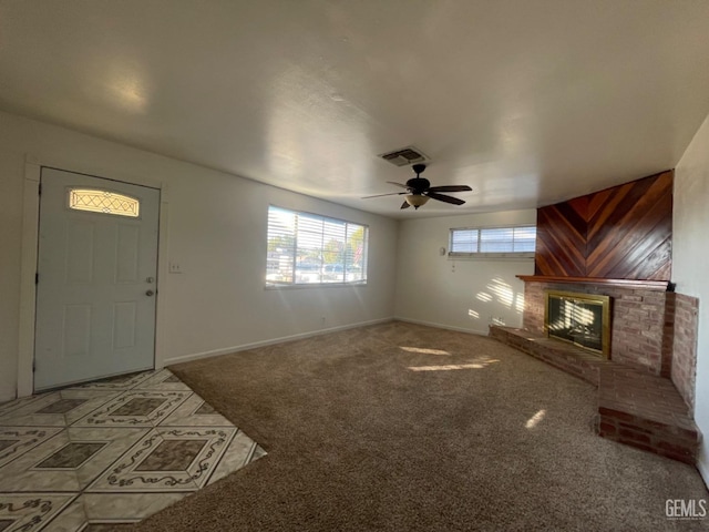 unfurnished living room with carpet floors, wood walls, a fireplace, and ceiling fan