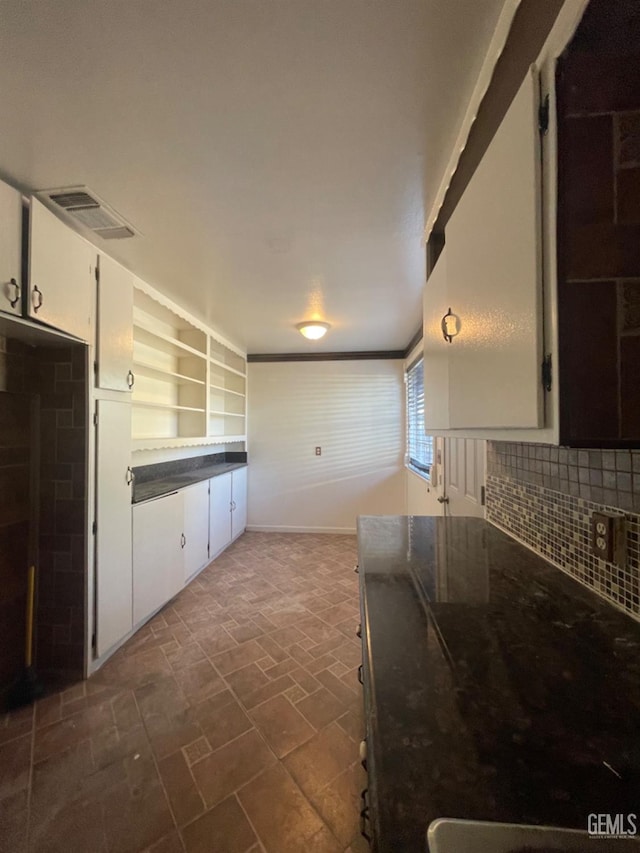 kitchen featuring decorative backsplash, white cabinetry, and ornamental molding