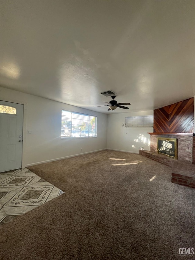 unfurnished living room with ceiling fan, carpet floors, and a fireplace