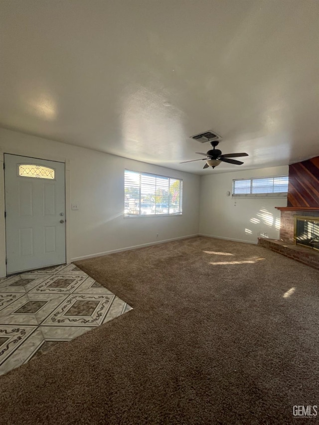 unfurnished living room featuring carpet flooring, ceiling fan, and a brick fireplace