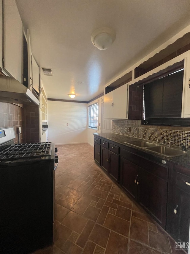 kitchen with white cabinets, black gas range, tasteful backsplash, and sink