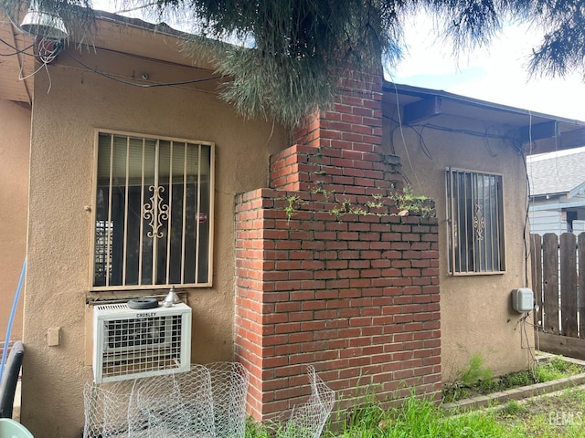 view of side of property with stucco siding and fence