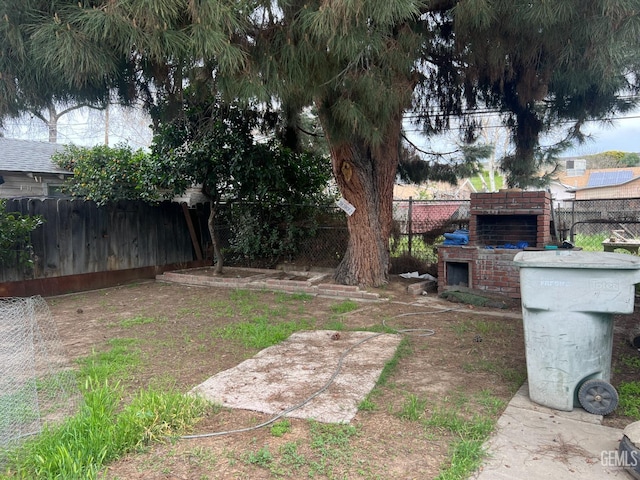 view of yard with a fireplace and a fenced backyard