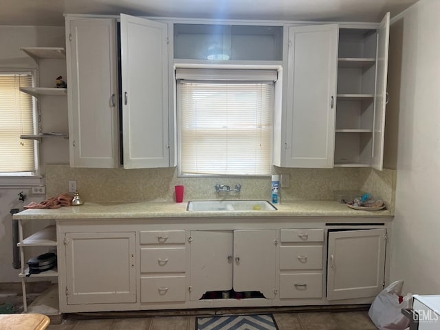 kitchen featuring open shelves, a sink, tasteful backsplash, white cabinetry, and light countertops