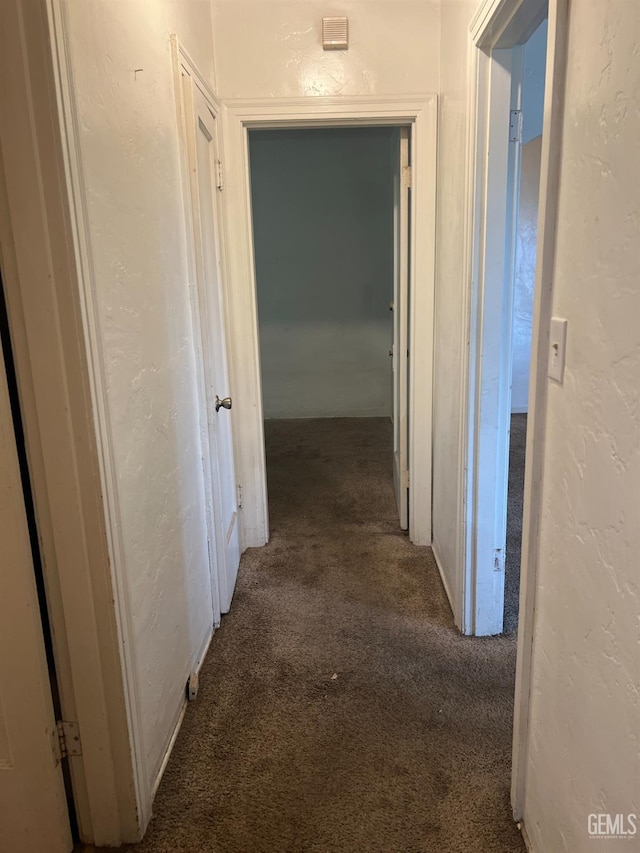 corridor featuring carpet floors and a textured wall