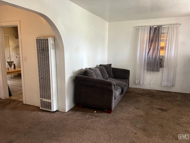 carpeted living area with arched walkways and a heating unit