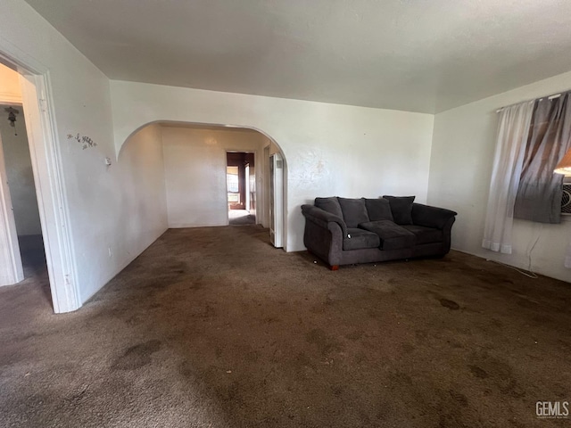 unfurnished living room featuring arched walkways and carpet floors