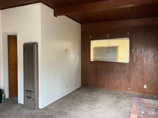 spare room featuring beamed ceiling, wooden walls, and carpet floors