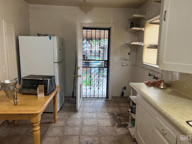 kitchen featuring open shelves, a toaster, white cabinets, and light countertops