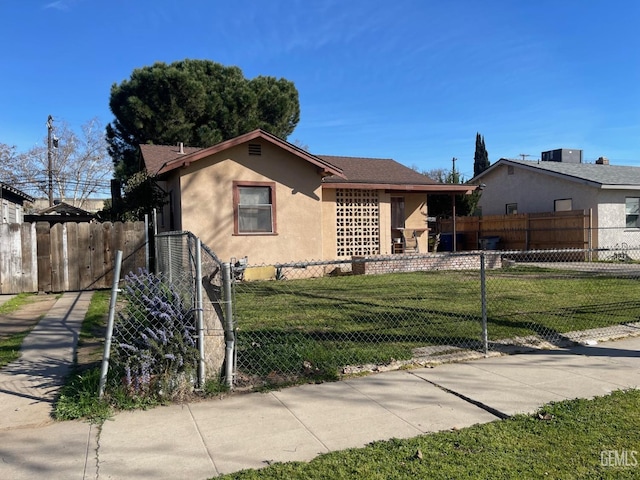 view of front of property featuring stucco siding, a fenced front yard, and a front lawn