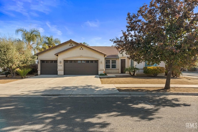 mediterranean / spanish-style home featuring an attached garage, concrete driveway, stucco siding, and a tile roof