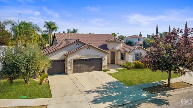 mediterranean / spanish-style home with concrete driveway, stucco siding, an attached garage, a front yard, and a tile roof