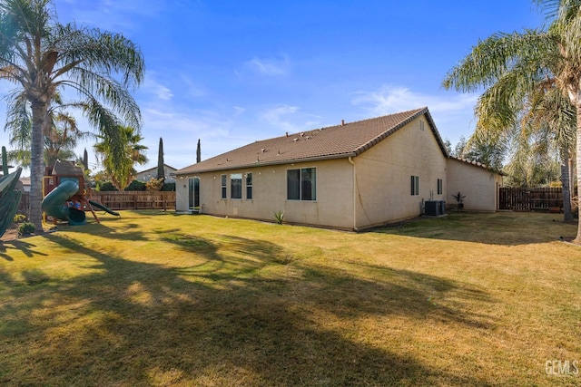 back of house with central AC, a tile roof, a yard, and stucco siding