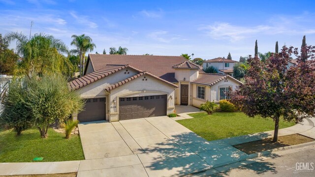 mediterranean / spanish home with a garage, concrete driveway, a tile roof, stucco siding, and a front lawn
