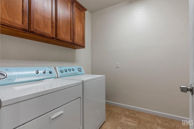 laundry room featuring washer and dryer, baseboards, and cabinet space
