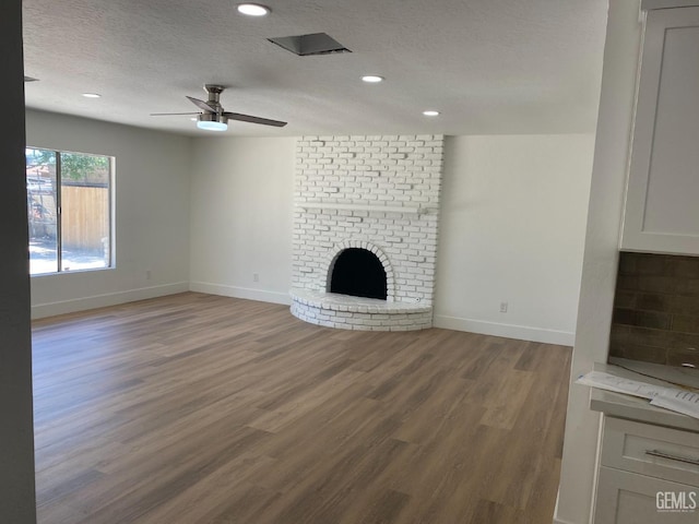 351 Adams St, Wasco, CA 93280 - unfurnished living room featuring a textured ceiling, baseboards, wood finished floors, ceiling fan, and a brick fireplace