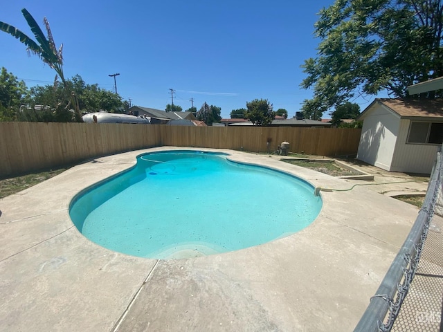 351 Adams St, Wasco, CA 93280 - view of swimming pool featuring a fenced backyard, a patio, an outbuilding, and a storage shed